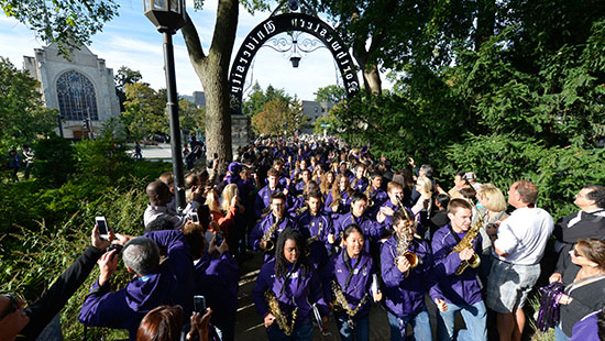 Students marching through the arch