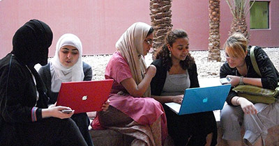 Group of Qatar students looking at laptops