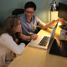 two people talking in front of a computer