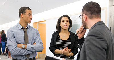 Female student in conversation with two male students