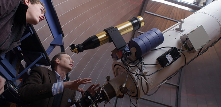 student and professor looking at a telescope